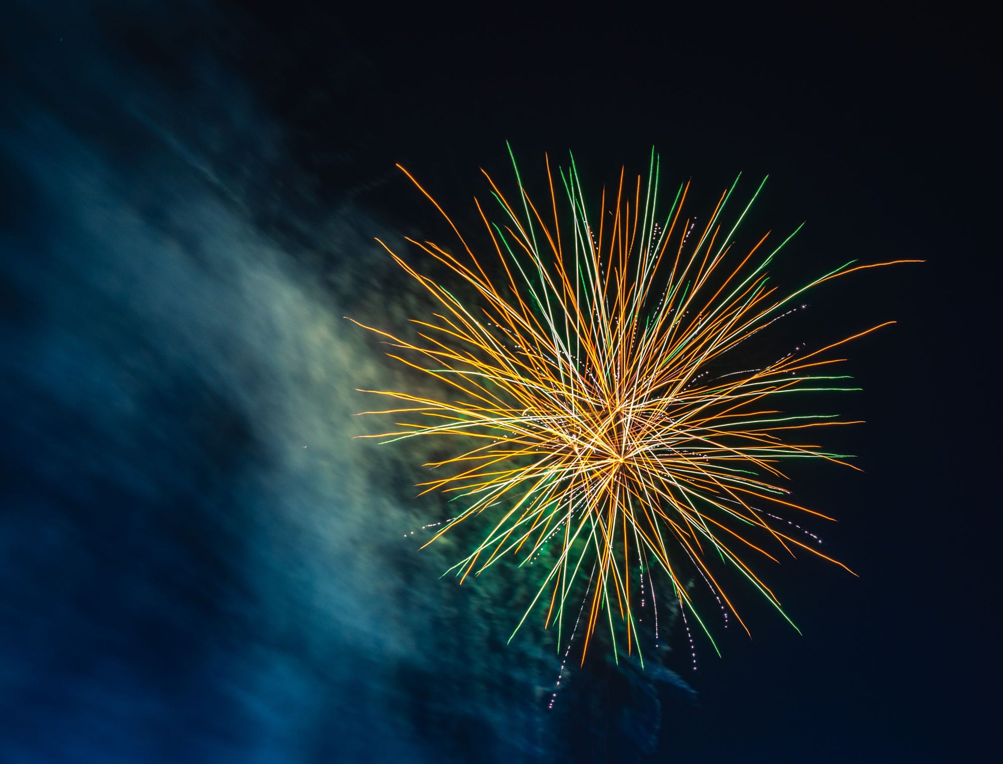 Feuerzeug für Feuerwerk gebraucht: eine Feuerwerksfontäne explodiert am dunklen Nachthimmel