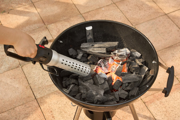 Elektrische BBQ aansteker blaast hete lucht op houtskool in een kogelbarbecue