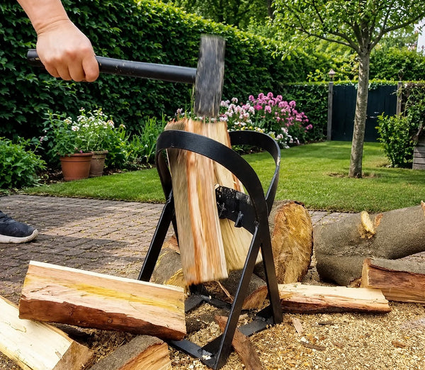 Gietijzeren houtklover splijt een blok met een hamerslag in de tuin